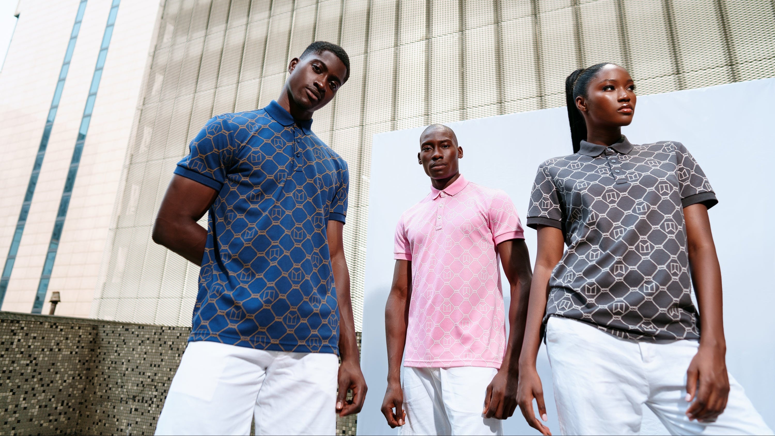 Three people wearing patterned twif Polo shirts standing in front of a building.